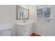 A bathroom with a white vanity, large mirror, a window and a white toilet at 29762 Spruce Rd, Evergreen, CO 80439