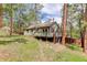 Exterior angled side view of home showcasing the wooden deck with railing, lush greenery, and mature trees at 29762 Spruce Rd, Evergreen, CO 80439