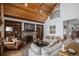 Elegant living room featuring a vaulted ceiling, stone fireplace, built-in bookshelves, and comfortable seating at 4075 Merada Ct, Franktown, CO 80116