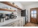 Bright pantry with open shelving, custom cabinetry, quartz countertops, and stainless steel refrigerator at 4075 Merada Ct, Franktown, CO 80116
