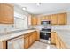 Functional kitchen with wooden cabinets, stainless steel appliances, and tiled countertops at 9621 W Chatfield Ave # F, Littleton, CO 80128