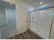 Modern bathroom featuring a glass-enclosed shower with tile surround and wood-look floors at 22023 E 38Th Pl, Aurora, CO 80019