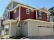 View of a stylish home featuring a two-car garage, red siding, gray stucco, and crisp white trim at 22023 E 38Th Pl, Aurora, CO 80019