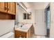 Compact bathroom with oak vanity, lighted mirror, and white tile flooring at 4081 Odessa St, Denver, CO 80249