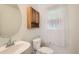 Cozy powder room featuring a pedestal sink, toilet, and a window with sheer curtains at 4081 Odessa St, Denver, CO 80249