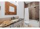 Stylish bathroom with decorative mirror, granite countertop, and shower-tub with decorative tile accent at 8278 Raphael Ln, Littleton, CO 80125