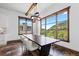 Sun-filled dining room with a modern chandelier, large windows overlooking the mountains, and a wood beam ceiling at 8278 Raphael Ln, Littleton, CO 80125