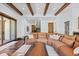 Bright living room with exposed wood beams, leather sofa, hardwood floors, and sliding glass doors to the outdoors at 8278 Raphael Ln, Littleton, CO 80125