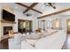 An open living area features a stone fireplace, wood beams, comfortable seating and lots of natural light at 8278 Raphael Ln, Littleton, CO 80125