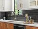 Modern kitchen featuring a stainless steel faucet, black backsplash, and stylish countertop decor with white and wood cabinets at 3001 S Ursula Cir # 101, Aurora, CO 80014