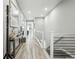 Modern hallway with light wood floors, neutral walls, and open staircase at 6469 Barnstead Dr, Castle Pines, CO 80108