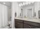 Well-lit bathroom with double sinks, granite countertops, and a shower with tub at 6591 N Ceylon St, Denver, CO 80249