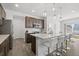 Bright kitchen featuring a large island, stainless steel appliances, dark cabinets, and hardwood flooring at 6591 N Ceylon St, Denver, CO 80249