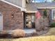 Close-up of the front door with decorative glass, brick exterior, manicured landscaping, and the American flag at 9930 W 82Nd Ave, Arvada, CO 80005