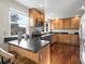 Bright kitchen features wood cabinets, dark granite countertops, and a large window overlooking a lush landscape at 9930 W 82Nd Ave, Arvada, CO 80005