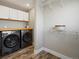 Bright laundry room featuring front load washer/dryer, wood floors, storage cabinets, and ample shelving at 9930 W 82Nd Ave, Arvada, CO 80005