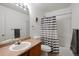 Standard bathroom with a tub and shower combination with gray striped curtain, single sink, and a toilet at 10405 Dresden St, Firestone, CO 80504