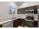 Well-equipped kitchen boasting stainless steel appliances, dark cabinets, and bright lighting at 10405 Dresden St, Firestone, CO 80504