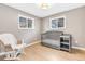 Cozy Bedroom with hardwood floors, a gray crib, and a rocking chair next to bright windows at 7727 W 81St Pl, Arvada, CO 80005