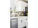 Bright kitchen boasts a stainless steel dishwasher, white cabinets and modern backsplash at 2875 Leyden St, Denver, CO 80207