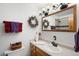 Charming bathroom with decorative wreath, wood vanity, and shower reflected in mirror at 11011 Kendall Way, Westminster, CO 80020
