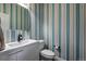 Stylish powder room with striped wallpaper, modern vanity, and toilet at 11345 W 38Th Ave, Wheat Ridge, CO 80033