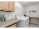 Bright laundry room with white washer and dryer, overhead shelving, and a folding counter at 12451 Turquoise Terrace Pl, Castle Pines, CO 80108