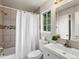 Bright bathroom with a white vanity, tiled shower, and a window providing natural light at 12599 Elm St, Thornton, CO 80241