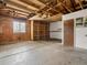 Unfinished garage with exposed wood ceiling, window, and door showing workshop potential at 12599 Elm St, Thornton, CO 80241