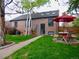 A manicured backyard area with a brick house and a table with a red umbrella for shade at 1315 Grape St, Denver, CO 80220