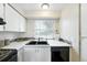 Cozy kitchen featuring a double sink, stylish backsplash, white cabinets, and modern appliances at 1978 Newland Ct, Lakewood, CO 80214