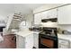 Compact kitchen with white cabinets, modern appliances, and staircase in the background at 1978 Newland Ct, Lakewood, CO 80214
