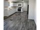 Modern kitchen with white cabinets, stainless steel appliances, and wood-look flooring at 3241 E 84Th Dr, Thornton, CO 80229