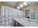 Bathroom featuring double sinks, a shower with floral curtain, large mirror, and updated lighting fixtures at 5189 S Malta Way, Centennial, CO 80015