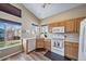 Sunlit kitchen features wood cabinets, white appliances, and a window overlooking the yard at 5189 S Malta Way, Centennial, CO 80015