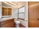 Bathroom showcasing a vanity with a single sink, toilet, and window with blinds at 10436 W 84Th Pl, Arvada, CO 80005