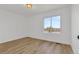 Empty bedroom with light wood floors and large bright window at 1260 Ascot Ave, Highlands Ranch, CO 80126