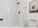 The shower features white tile, a gold showerhead and gold accents at 1260 Ascot Ave, Highlands Ranch, CO 80126