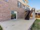 Brick house featuring sliding glass door, concrete patio, and wooden stairs to upper deck at 4816 S Elk Way, Aurora, CO 80016