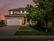 Charming two-story home featuring a brick facade and well-manicured lawn at dusk at 4816 S Elk Way, Aurora, CO 80016