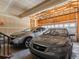 Two-car garage with unfinished ceiling, overhead door and 2 gray vehicles at 4816 S Elk Way, Aurora, CO 80016