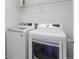 Functional laundry room with modern white washer and dryer and overhead storage at 4816 S Elk Way, Aurora, CO 80016