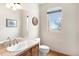 Bright powder room featuring a vanity with tile countertop, a decorative mirror, and natural light from a window at 7724 Kryptonite Ln, Castle Rock, CO 80108