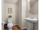 Modern powder room features a pedestal sink, oval mirror, and stylish hardwood floors at 9071 E Phillips Dr, Centennial, CO 80112