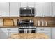 Updated kitchen featuring stainless steel appliances, granite counters, and white cabinetry at 9071 E Phillips Dr, Centennial, CO 80112