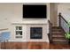 Spacious living room featuring a fireplace, television, staircase, and wood flooring at 9071 E Phillips Dr, Centennial, CO 80112