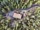 Aerial view of a beautiful brown home with a long driveway nestled in a dense forest setting at 29825 Kennedy Gulch Rd, Conifer, CO 80433
