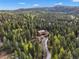 Aerial view of home nestled in lush forest with driveway at 29825 Kennedy Gulch Rd, Conifer, CO 80433