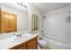 Bright, tiled bathroom featuring a shower-tub combo, clean white fixtures, and wooden vanity at 29825 Kennedy Gulch Rd, Conifer, CO 80433