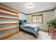 Charming bedroom with a single bed, wooden shelves, and window with natural light, complemented by floral wallpaper at 29825 Kennedy Gulch Rd, Conifer, CO 80433
